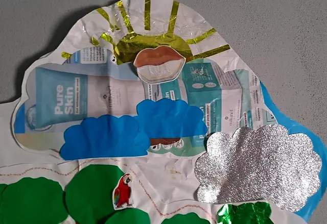 Detalle del mural: sol de papel dorado, nubes celestes y plateadas, árboles