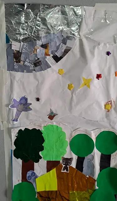 Detalle del mural: hada violeta recortada sobre papel plateado, estrellas de cartulina, árboles y gato negro